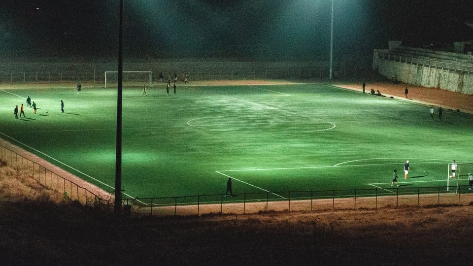 Terrain de football éclairé la nuit avec des joueurs sur la pelouse